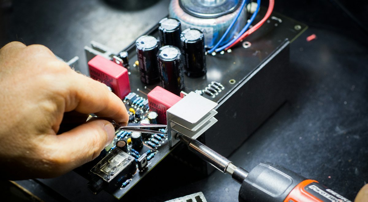 A technician's hands repairing computer hardware with a screwdriver